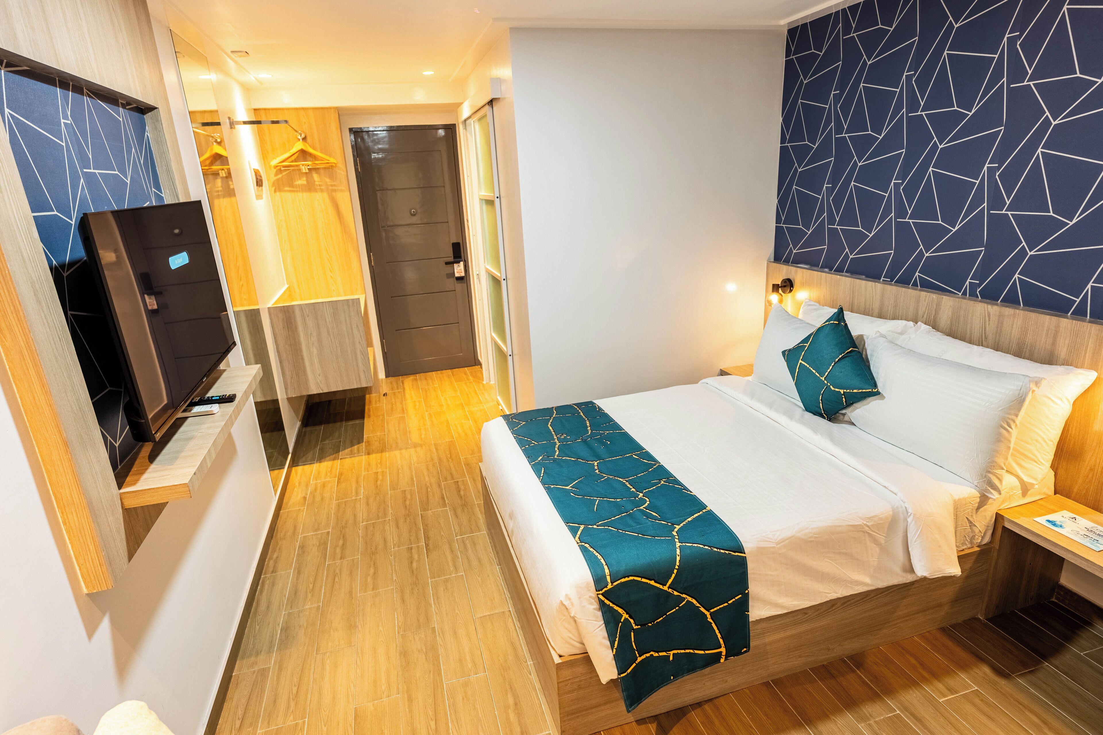 A hotel room with a bed, a TV, a wardrobe, and a door to a bathroom.
