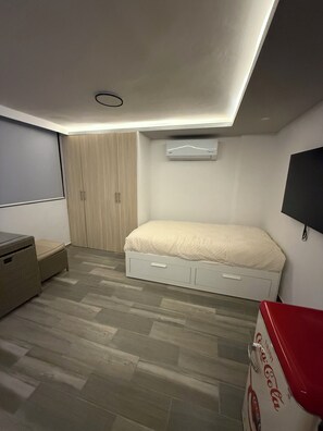 A bedroom with a bed, wardrobe, and a television. - Tranquil 1-bedroom hotel suites with AC in Gro,
2 pools and Jacuzzy (Gro.)