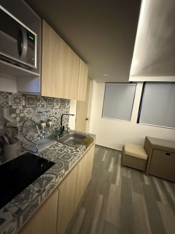 Una cocina moderna con microondas, pileta y salpicadero estampado.