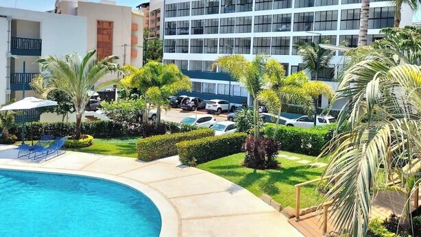 Un hotel con piscina, palme e parcheggio.