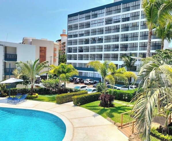 Ein Hotel mit Pool, Palmen und einem Parkplatz.