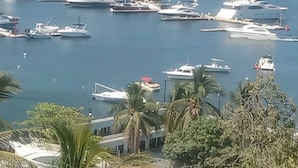 Una marina con diverse imbarcazioni ormeggiate, circondata da un paesaggio urbano costiero.