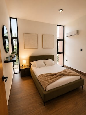 A modern bedroom with a large bed, bedside tables, a mirror, and artwork on the walls. - Cozy 1-bedroom apartment in fantastic Punta Cana with AC (Punta Cana)