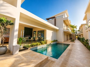 A modern building with a swimming pool, outdoor seating, and a staircase. - Cozy 1-bedroom apartment in fantastic Punta Cana with AC (Punta Cana)
