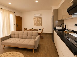 Una cocina moderna con encimera negra, horno integrado y aire acondicionado de pared.