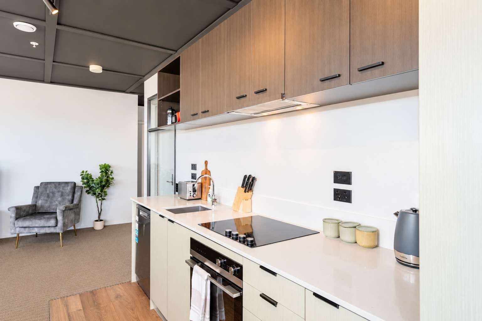 A modern kitchen with wooden cabinets, a black countertop, and a built-in oven.