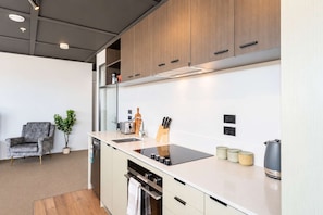 Une cuisine moderne avec des meubles en bois, un plan de travail noir et un four encastré.