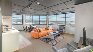Un salon moderne avec un canapé, une table basse et une vue sur la ville grâce à de grandes fenêtres.