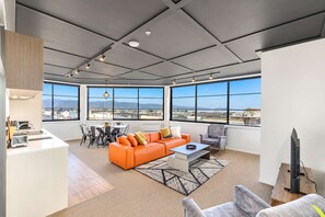 A modern living space with a large window, a sofa, a coffee table, and a dining area.