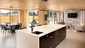 A modern kitchen with a large island, dining area, and a stone accent wall. - Enjoy Your Own Private Pool and Backyard Oasis in Windsor (Windsor)