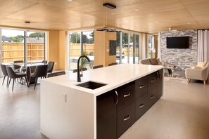 A modern kitchen with a large island, dining area, and a stone accent wall. - Enjoy Your Own Private Pool and Backyard Oasis in Windsor (Windsor)
