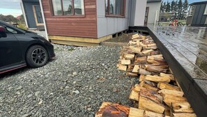 A modern building with a gravel driveway and a firewood stack. - Rural Retreat: Group Bookings, Family Adventures & Work Trips (Lumsden)