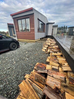 A modern building with a gravel driveway and a firewood stack.
