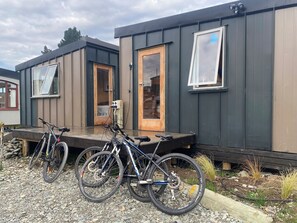 A modern, compact building with two visible doors and windows, a gravel driveway, and bicycles parked in front. - Rural Retreat: Workshops, Family Reunion, Work Trip, Mini Conference, Adventure. (Lumsden)