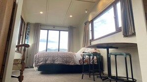 A bedroom with a bed, a window, a chair, and a wooden door. - Rural Retreat: Group Bookings, Family Adventures & Work Trips (Lumsden)