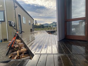 A modern building with a wooden deck, a bike, and a pile of firewood.