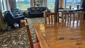 A living room with a wooden dining table, leather sofas, and a view of the outdoors. - Rural Retreat: Group Bookings, Family Adventures & Work Trips (Lumsden)