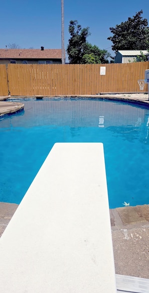 A swimming pool with a wooden fence and a basketball hoop. - Midtown Oasis 
3 Bedrooms house in  Rogers with  AC, private pool and more (Rogers)