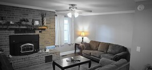 Ein Wohnzimmer mit Kamin, Deckenventilator, einer Couch und einem Couchtisch.