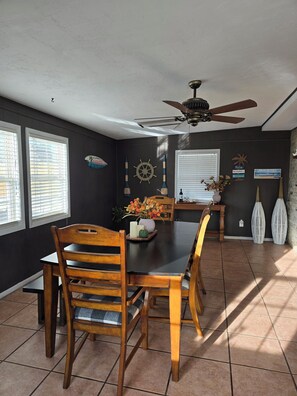 A dining area with a table, chairs, a ceiling fan, and decorative wall elements. - Midtown Oasis
3 Bedrooms house in Rogers with AC, private pool and more (Rogers)