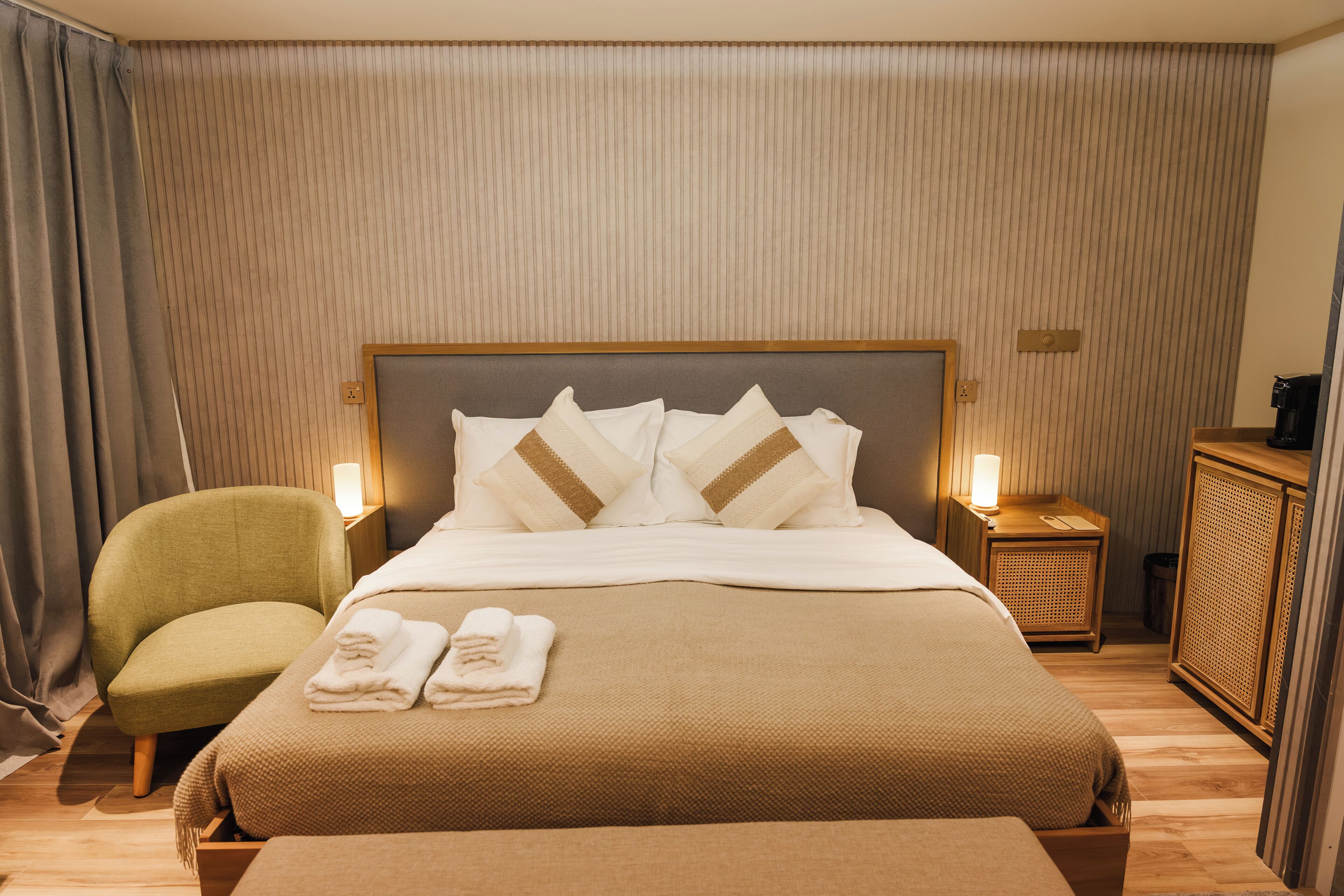 Une chambre d’hôtel avec un lit, une chaise, une table de chevet et un placard.