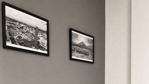 Une chambre à coucher avec un lit, deux oreillers, une tête de lit et deux tableaux encadrés accrochés au mur.