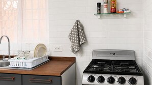 Une cuisine équipée d’une cuisinière, de placards, d’un égouttoir et d’une poubelle.