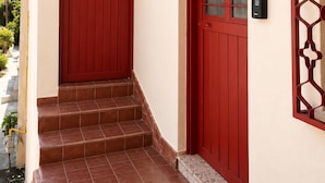 Une porte rouge avec un panneau de verre, le numéro « 116 A » au-dessus, et une petite marche menant à l’entrée.