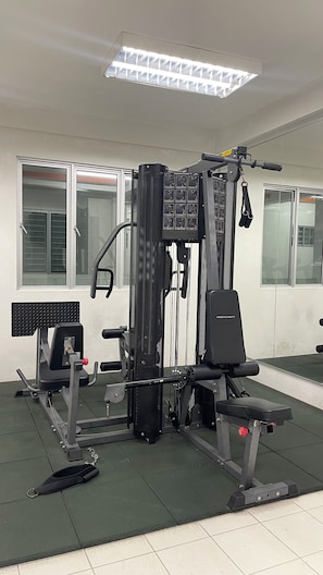 Ein Fitnessraum mit Hantelgestell, Bankdrücker und verschiedenen Krafttrainingsgeräten.