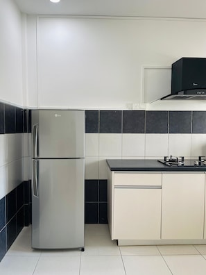 Eine Küche mit einem Edelstahlkühlschrank, einer schwarzen Mikrowelle und einem Gasherd.