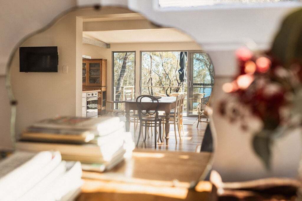 A room with a large window, a dining table, and a television.