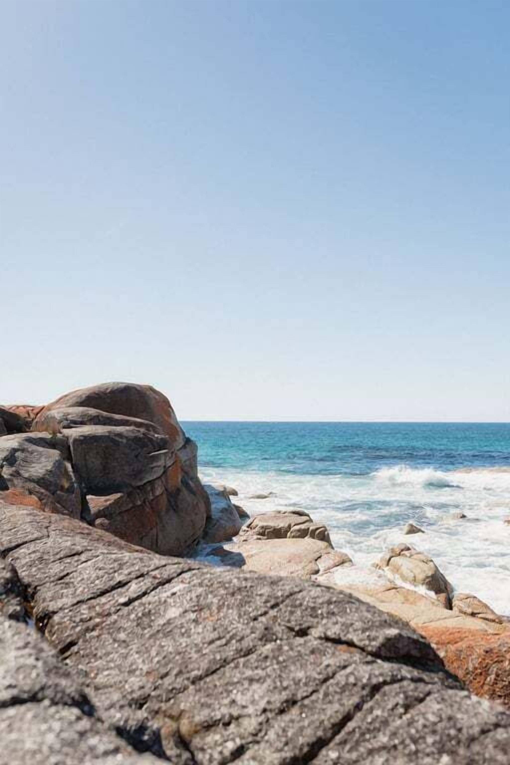 A rocky coastline with large boulders and the ocean in the background.