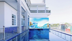 Una piscina amb un mural, un balcó amb barana i la façana d'un edifici.