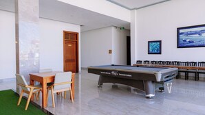 Taula de bitlles en una habitació amb sòl de marbre, una porta de fusta i un quadre al mur.