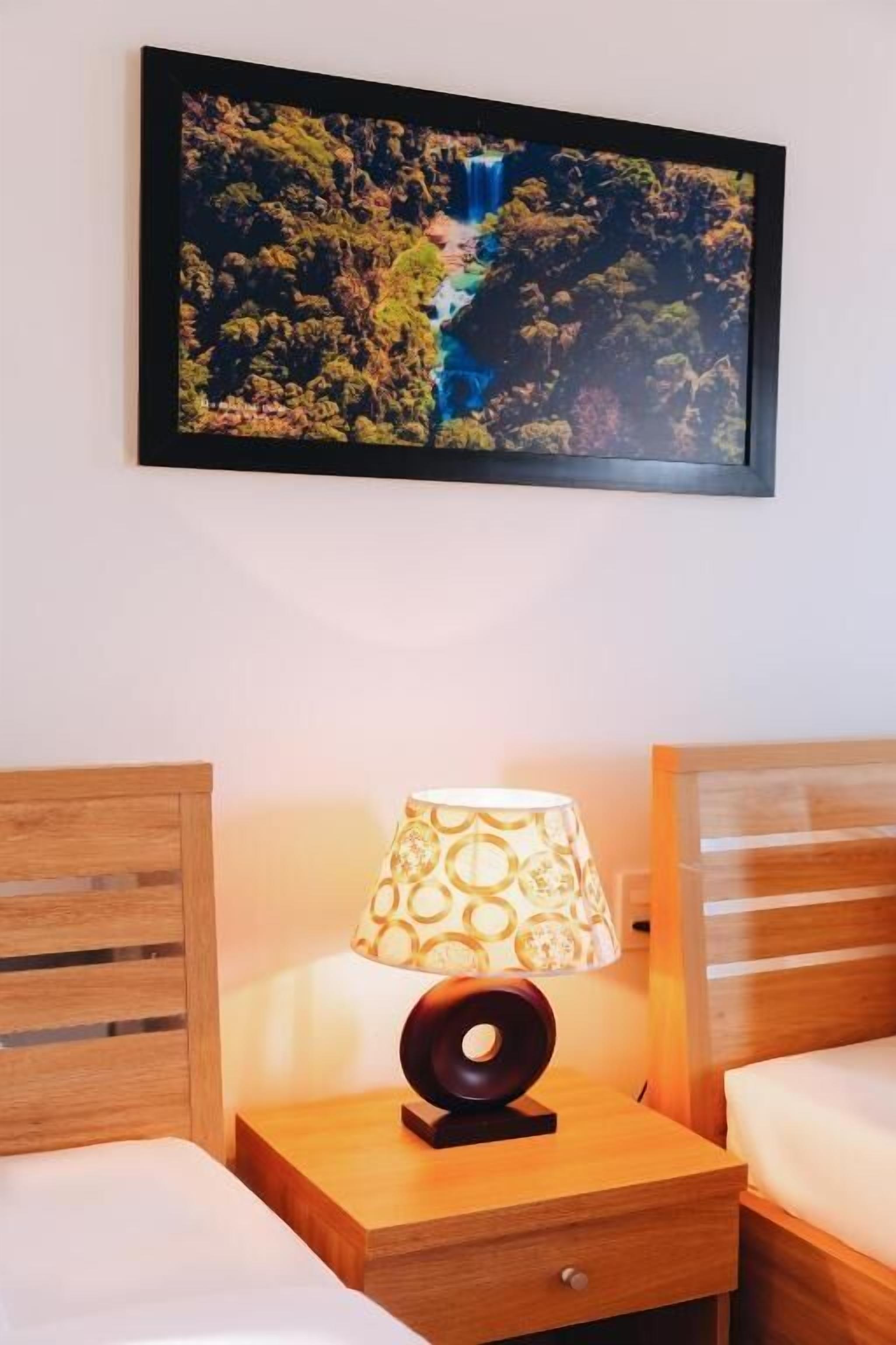 A hotel room with a bed, a nightstand with a lamp, and a framed picture of a waterfall.