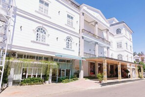 Un hotel de varios pisos con entrada techada, amplias ventanas y un balcón.