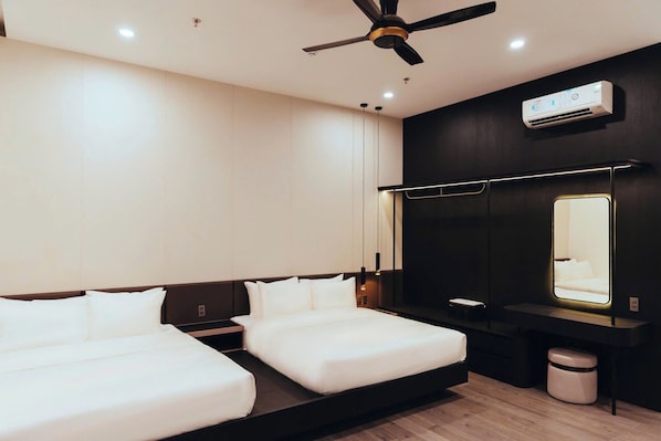 Una habitación de hotel moderna con cama, mesitas de noche, ventilador de techo, equipo de aire acondicionado, un espejo grande y un pequeño bote de basura.