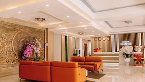 Un vestíbul d'hotel modern amb un sofà modular, una paret decorativa i una taula de recepció.