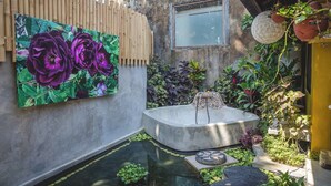 A courtyard with a concrete bathtub, a wooden fence, and a large painting of purple flowers. - 1BR in the heart of Ubud - Tiny Bali (Ubud)
