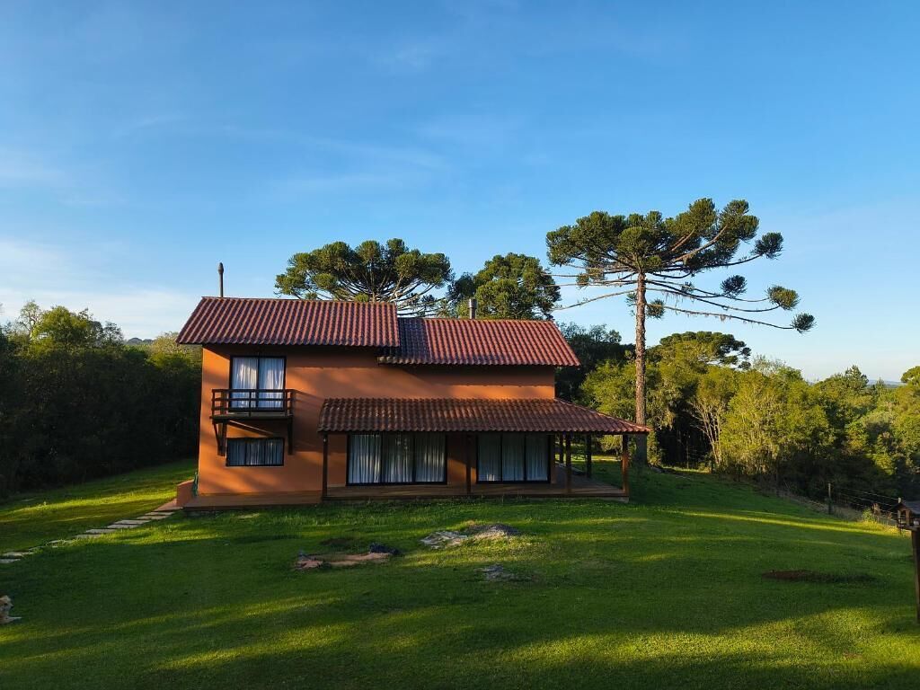 Een woonhuis met twee verdiepingen, een rood dak, een balkon op de bovenverdieping en een overdekte veranda.