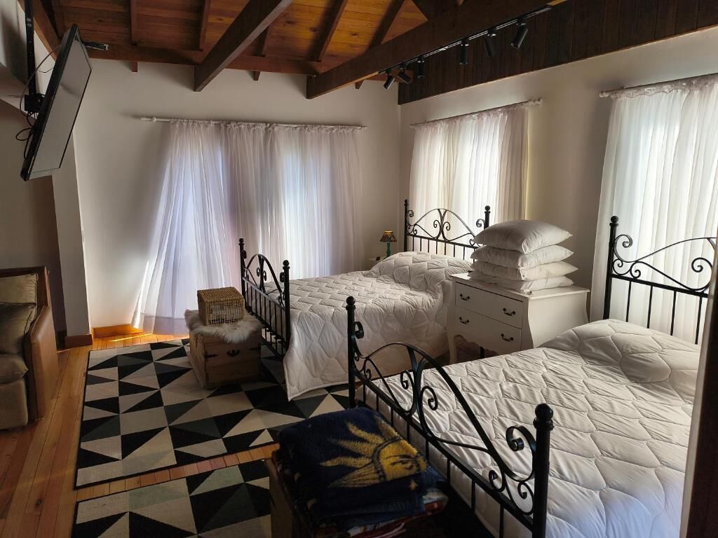 Een slaapkamer met drie bedden, een houten plafond en een geruit vloerkleed.