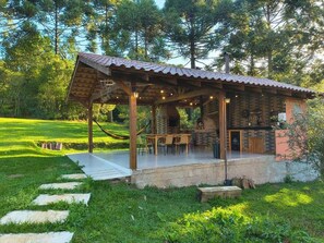 A rustic outdoor seating area with a wooden pergola, stone steps, and a concrete patio. - Country house in Lages, Aconchego Serrano, with outdoor hot tub. (Lages)