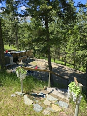 A stone pathway leading to a wooden deck with a bench, surrounded by trees.