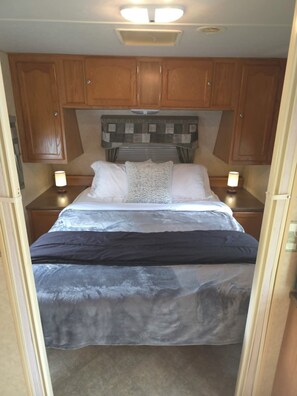Makuuhuone, jossa on sänky, puiset kaapit ja kaksi yöpöytävalaisinta.