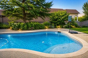 Ein Schwimmbecken mit gewölbter Kante, umgeben von einem Kiesstreifen.