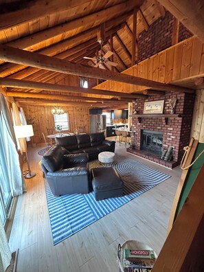 Ein gemütliches Wohnzimmer mit Kamin, Essbereich und Küche in einer Blockhütte.