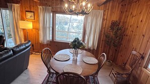 Um interior em madeira com uma mesa de jantar redonda, cadeiras, um candelabro e um sofá.
