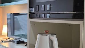 Een kitchenette met een koffiezetapparaat, een magnetron en een kleine koelkast.