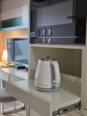 Eine Küchenzeile mit Kaffeemaschine, Mikrowelle und kleinem Kühlschrank.