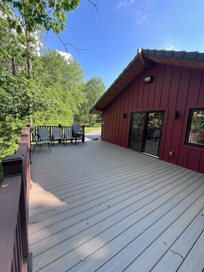 A wooden deck with outdoor furniture, a building with a red exterior, and a clear blue sky. - NEW , Spacious , Modern 4-bedroom Red House in peaceful  Westfield (Westfield)